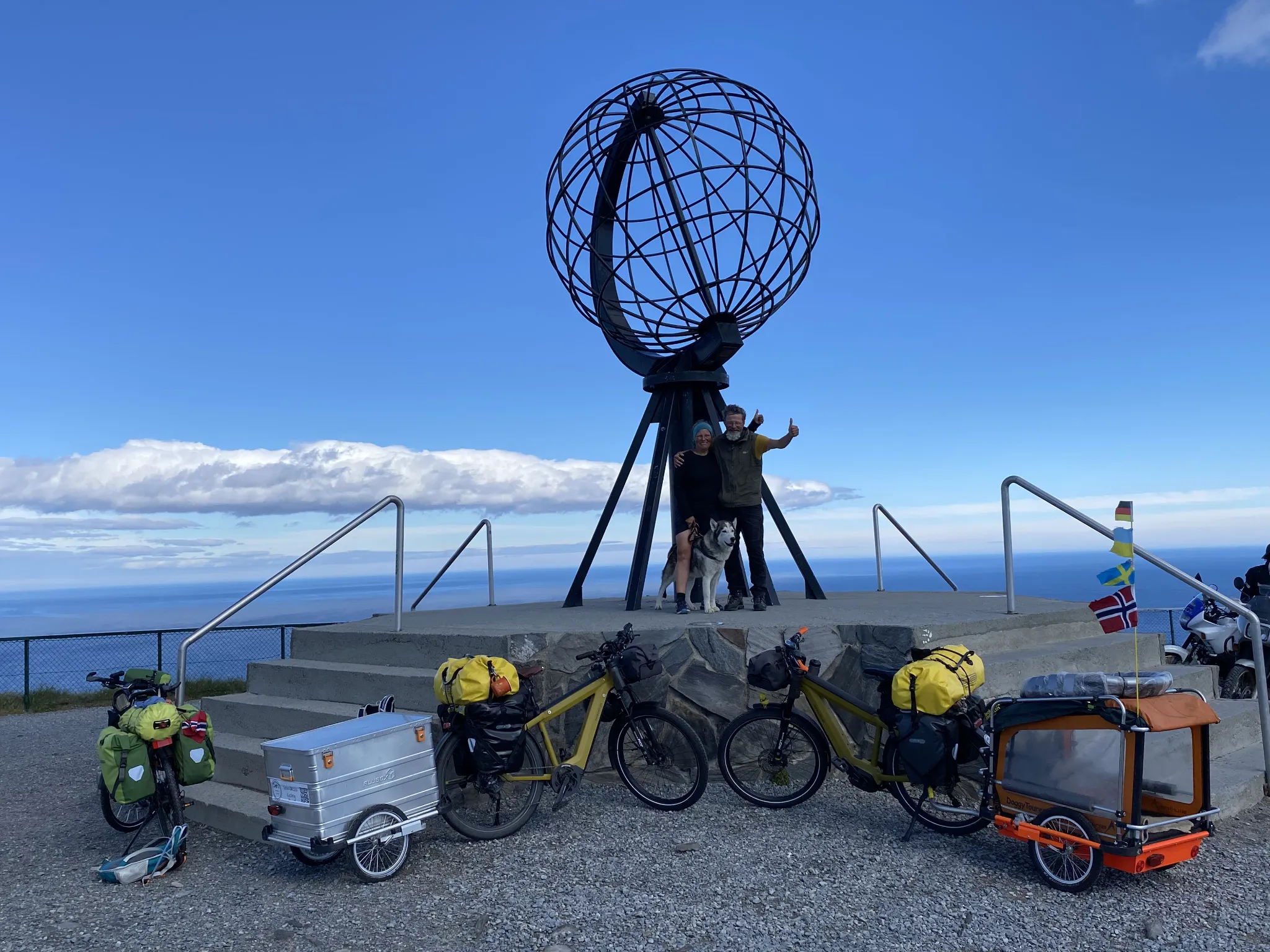 Tanja, Rene und Anouk mit ihren Fahrrädern unter der Weltkugel am Nordkap, aufgenommen am 15. Juli 2022